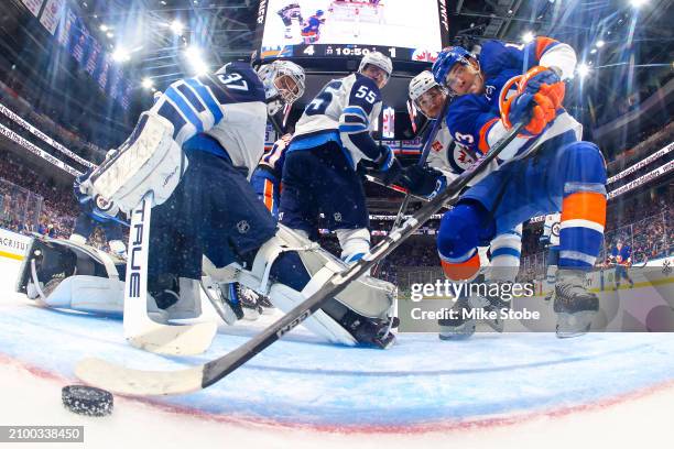 Mathew Barzal of the New York Islanders scores a goal past Connor Hellebuyck of the Winnipeg Jets as Neal Pionk defends during the second period at...