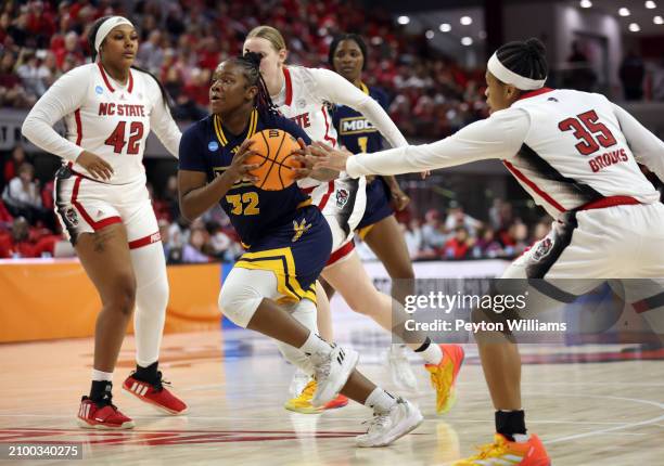 Raven Thompson of the Chattanooga Lady Mocs drives against Mallory Collier of the North Carolina State Wolfpack and Zoe Brooks of the North Carolina...
