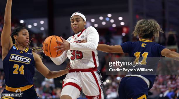 Zoe Brooks of the North Carolina State Wolfpack drives against Jada Guinn and Caia Elisaldez of the Chattanooga Lady Mocs during the first round of...