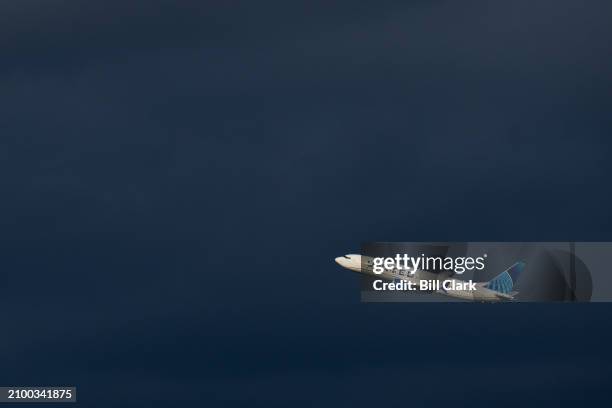 United Airlines Boeing 737 MAX 8 plane takes off past dark rain clouds from Ronald Reagan Washington National Airport in Arlington, Va., on Saturday,...