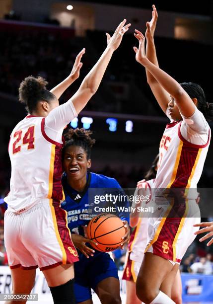 Paige Allen of the Texas A&M Corpus Christi Islanders drives to the basket between Kaitlyn Davis of the USC Trojans and Rayah Marshall of the USC...