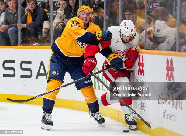 Tyson Barrie of the Nashville Predators hits Joe Veleno of the Detroit Red Wings during an NHL game at Bridgestone Arena on March 23, 2024 in...