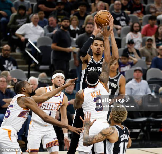 Victor Wembanyama of the San Antonio Spurs looks to pass to Jeremy Sochan over Bradley Beal of the Phoenix Suns in the second half at Frost Bank...