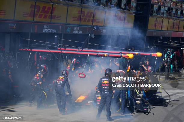 Mechanics deal with the smoke coming out of Red Bull Racing's Dutch driver Max Verstappen car during the Australian Formula One Grand Prix at Albert...