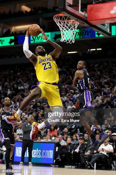 LeBron James of the Los Angeles Lakers dunks the ball on De'Aaron Fox of the Sacramento Kings at Golden 1 Center on March 13, 2024 in Sacramento,...