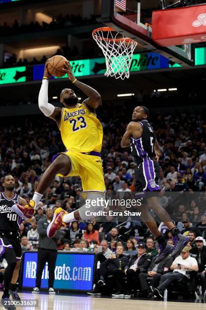 LeBron James of the Los Angeles Lakers dunks the ball on De'Aaron Fox of the Sacramento Kings at Golden 1 Center on March 13, 2024 in Sacramento,...