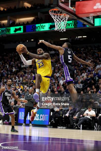 LeBron James of the Los Angeles Lakers dunks the ball on De'Aaron Fox of the Sacramento Kings at Golden 1 Center on March 13, 2024 in Sacramento,...