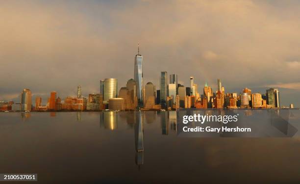 Faint rainbow appears behind the skyline of lower Manhattan and One World Trade Center as the sun sets in New York City on March 20 as seen from...