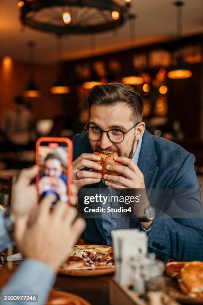 "savvy businessman refueling with a delicious burger during a hectic day - classic day 4 stock pictures, royalty-free photos & images