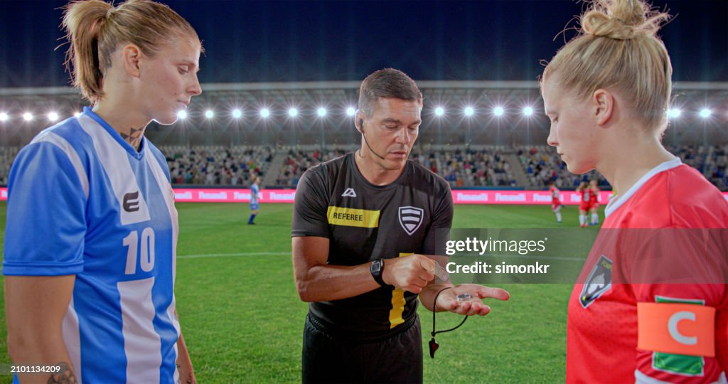 Referee with team captions on football pitch