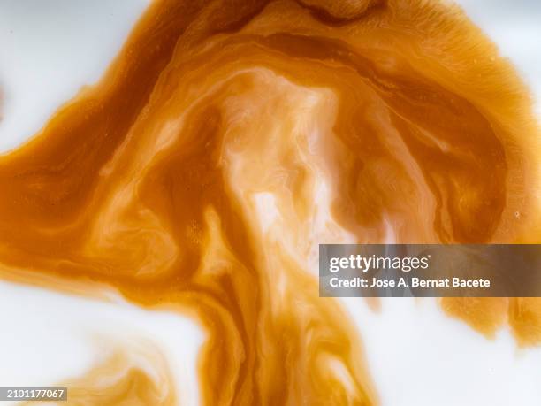 full frame, mixing some espresso coffee with blended milk in the cup. - image stock pictures, royalty-free photos & images