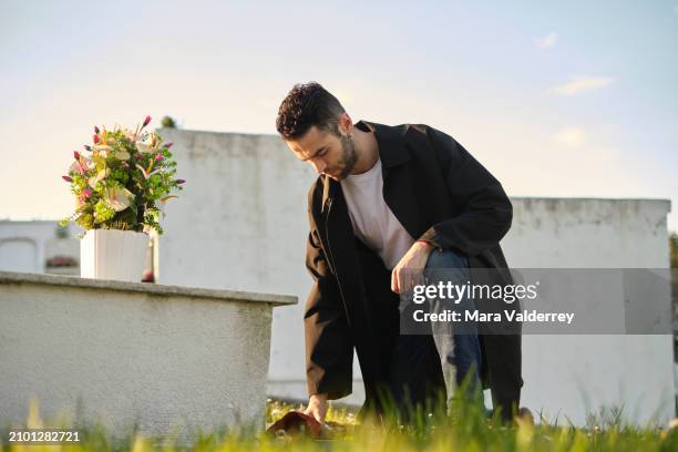 sad man bringing flowers at the cemetery - cemetery stock pictures, royalty-free photos & images