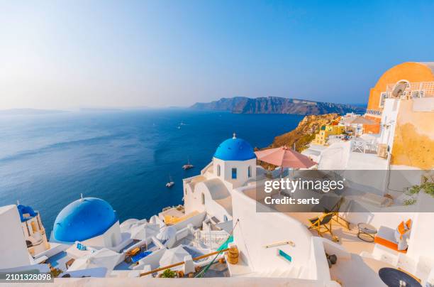 beautiful summer vacation landscape of iconic blue domed churches along the caldera edge at sunny morning against clear blue sky in oia, santorini, caldera, greek islands, greece - mediterranean-blue-roof-santorini stock pictures, royalty-free photos & images