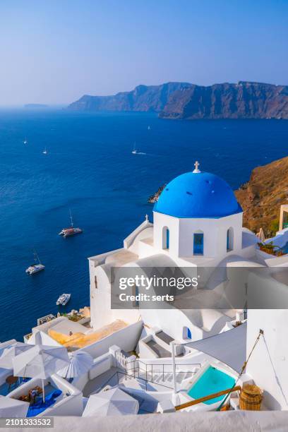 beautiful summer vacation landscape of iconic blue domed churches along the caldera edge at sunny morning against clear blue sky in oia, santorini, caldera, greek islands, greece - santorini imagens e fotografias de stock