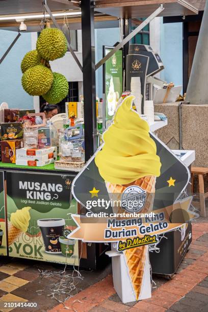 durian fruits and an advertisement for durian ice cream - malaysian road stock pictures, royalty-free photos & images