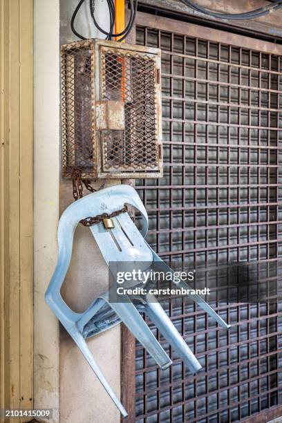 plastic chair hanging in a chain with a padlock - malaysian road stock pictures, royalty-free photos & images