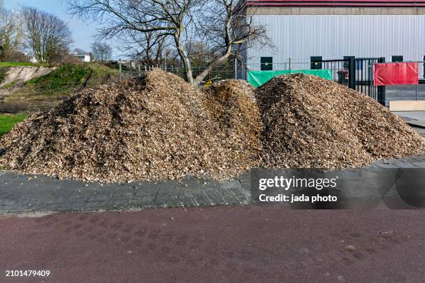 mountain of wood chip waste lying on a lawn - wood chip stock pictures, royalty-free photos & images
