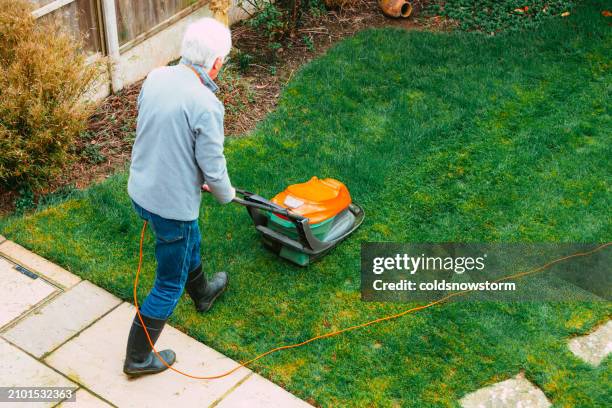 high angle view of man mowing lawn in back garden - garden machinery stock pictures, royalty-free photos & images