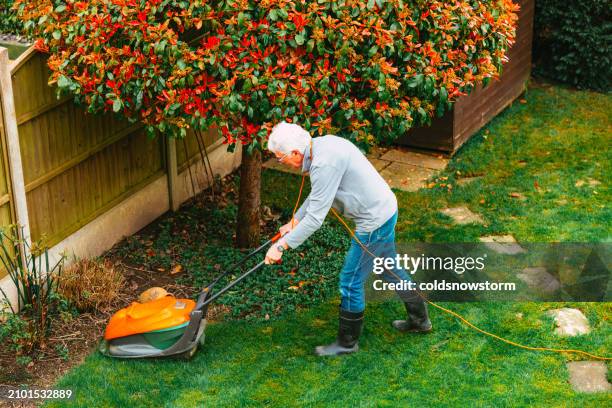 high angle view of man mowing lawn in back garden - garden machinery stock pictures, royalty-free photos & images