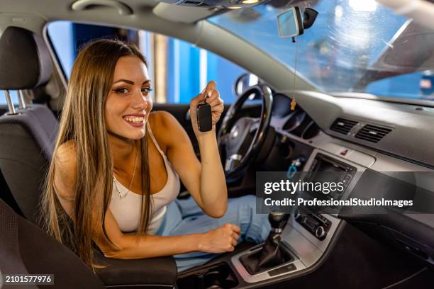 a beautiful young woman in a car is taking keys of a car in a service workshop. - happy client by broken car stock pictures, royalty-free photos & images