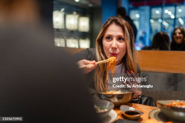 junge frau geht mit ihrer freundin nudeln zum abendessen essen - evento su pista stock-fotos und bilder