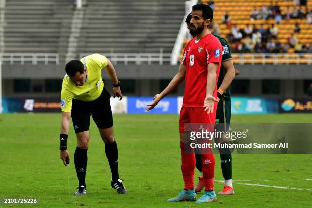 The referee puts a mark on the pitch before a corner kick during the 2026 FIFA World Cup Qualifiers second round Group G match between Pakistan and...