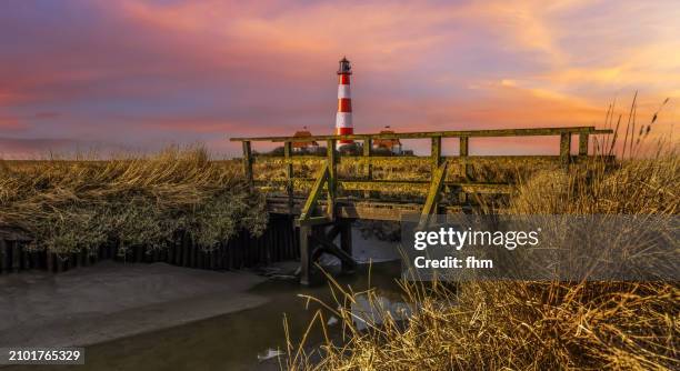 travel destination: westerhever lighthouse at sunset (schleswig-holstein, germany) - westerhever vuurtoren stockfoto's en -beelden