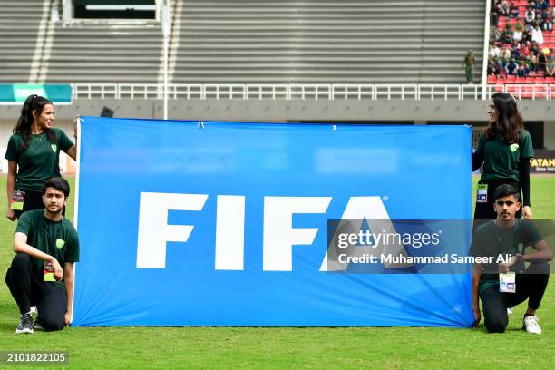 Volunteers hold a FIFA flag during anthems prior to the 2026 FIFA World Cup Qualifiers second round Group G match between Pakistan and Jordan at...