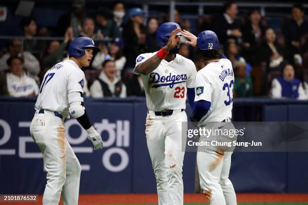 Jason Heyward of the Los Angeles Dodgers celebrates with teammates Shohei Ohtani and James Outman after scoring a run by a RBI single of Mookie Betts...