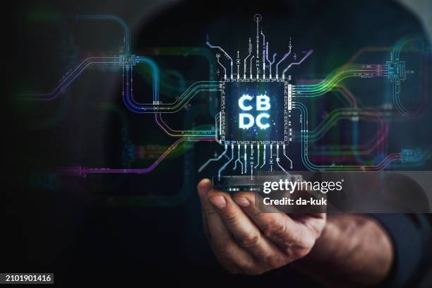 cbdc in your hand. male hand holding futuristic cbdc chip in the center and circuit board with vibrant data transfers, representing evolving payment technology of the future. - digital currency stock pictures, royalty-free photos & images