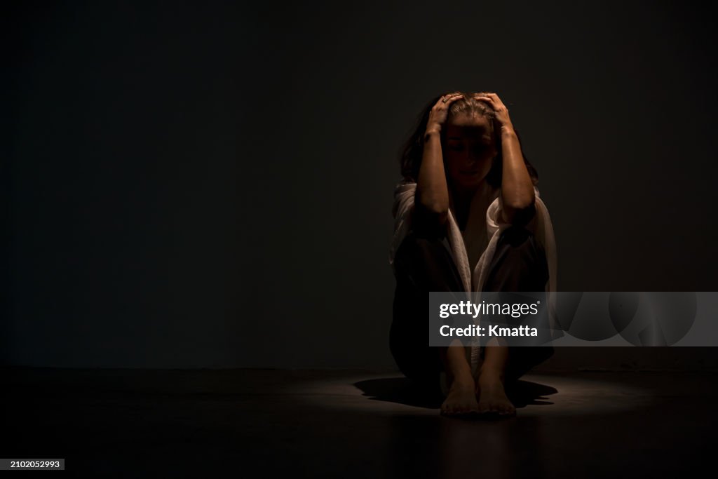 Stressed anxious woman sitting on floor hugging knees feeling scared, depression and mental health concept.