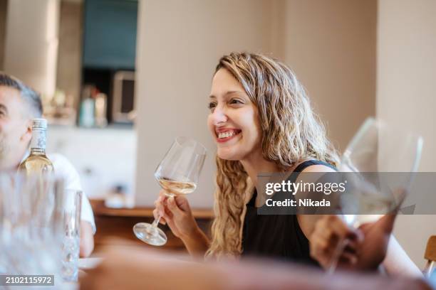 smiling woman enjoying wine with friends at gathering - dinner party stock pictures, royalty-free photos & images
