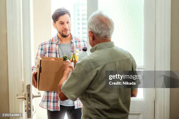young man delivering groceries to elderly homeowner - food safety audit stock pictures, royalty-free photos & images