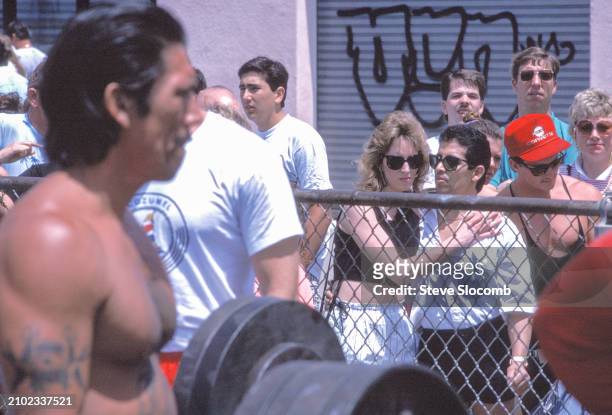 View of onlookers at Muscle Beach at Venice Beach, Los Angeles, California, 1990. Visible out of focus at fore left, is American actor Danny Trejo,...