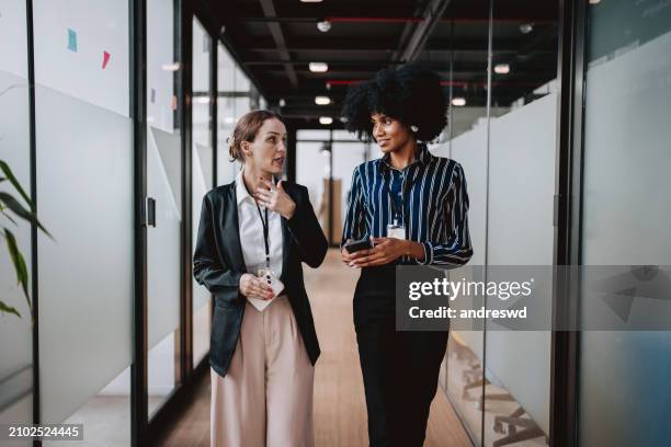 employees walking down the company corridor - colleague stock pictures, royalty-free photos & images