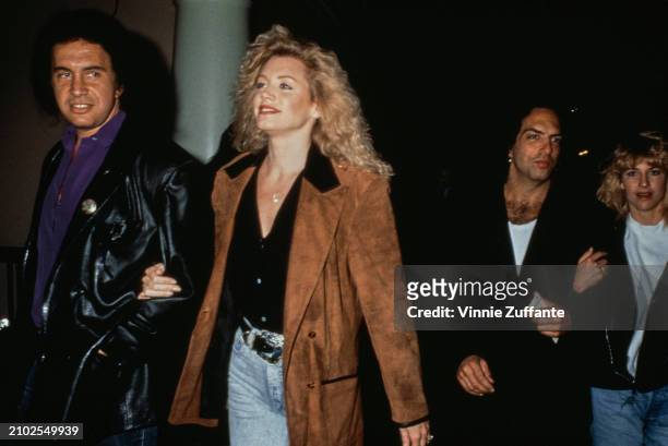 American musician Gene Simmons, wearing a black leather jacket, arm-in-arm with Canadian actress and glamour model Shannon Tweed, who wears a brown...