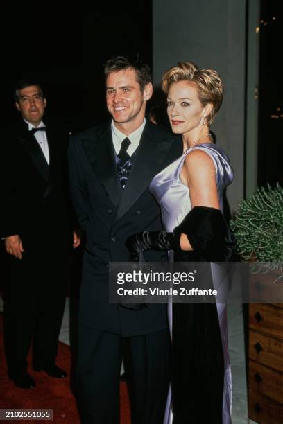 Canadian actor and comedian Jim Carrey, wearing a black double-breasted suit, and American actress Lauren Holly, who wears a sapphire blue evening...