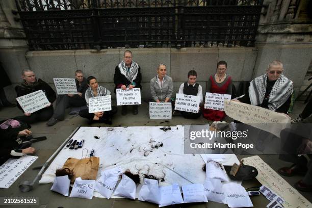 Protesters with their newly shaved heads hold signs outlining the plight of those in Gaza around the centrepiece of a sheet covered with hair...