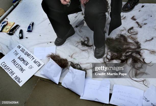 Protester sits surrounded by locks of her hair and envelopes containing other protesters hair in support of the women of Gaza outside the Houses of...