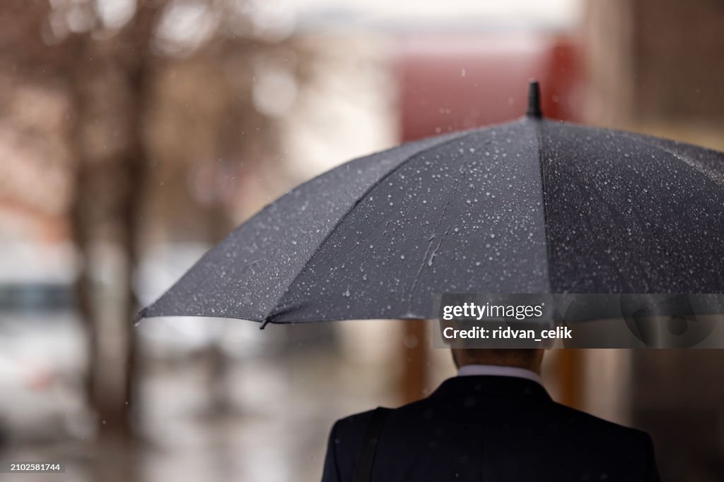 Portrait of businessman in rain in city