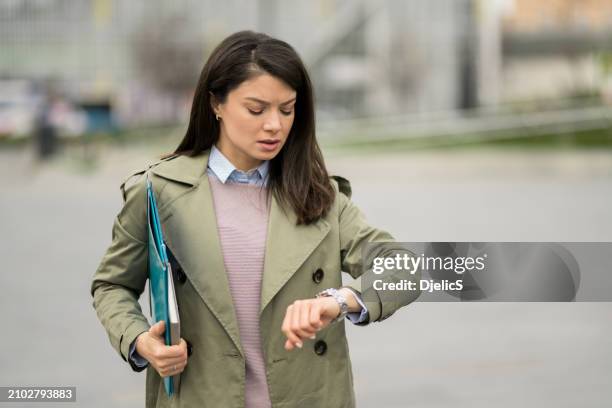 young businesswoman checking time on her watch while being late for work. - watch now stock pictures, royalty-free photos & images