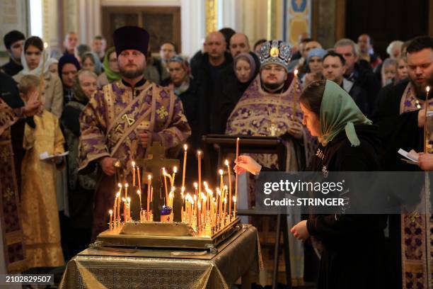 Woman places a lit candle as people attend a memorial service at the Alexander Nevsky Cathedral in Simferopol, Crimea, on March 24 as Russia observes...