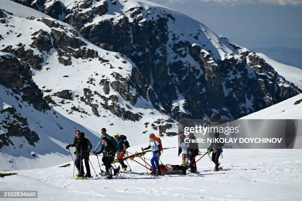 Volunteers pull a person with disabilities on a snow stretcher, under the Little Kabul peak at 2507 meter high, as they climb the Rila Mountain,...