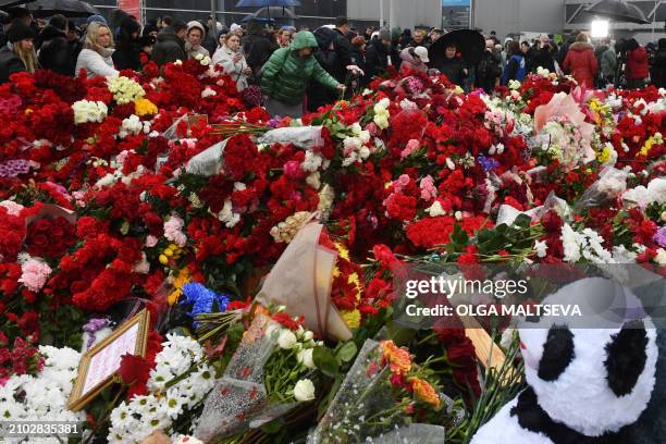 People lay flowers at a makeshift memorial in front of the Crocus City Hall in Krasnogorsk on March 24 as Russia observes a national day of mourning...