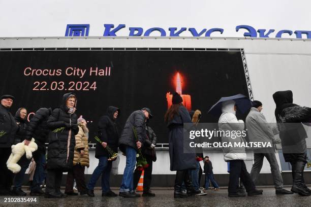 Mourners stand in a queue to lay flowers at a makeshift memorial in front of the Crocus City Hall in Krasnogorsk on March 24 as Russia observes a...