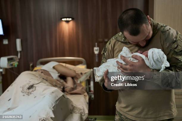 Dmytro "Drongo" holds his newborn as his wife Lyubov rests after childbirth at the KNP Perinatal Center at the KNP Perinatal Center on March 23, 2024...
