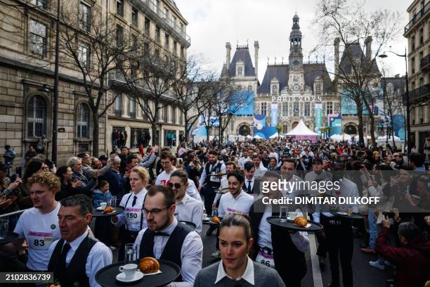 Waiters and waitresses in work outfits take the start of a traditionnal "Course des cafes" , in front of the City Hall in central Paris, on March 24,...