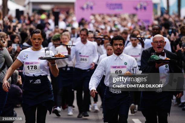 Waiters and waitresses in work outfits compete in a traditionnal "Course des cafes" , in front of the City Hall in central Paris, on March 24, 2024....