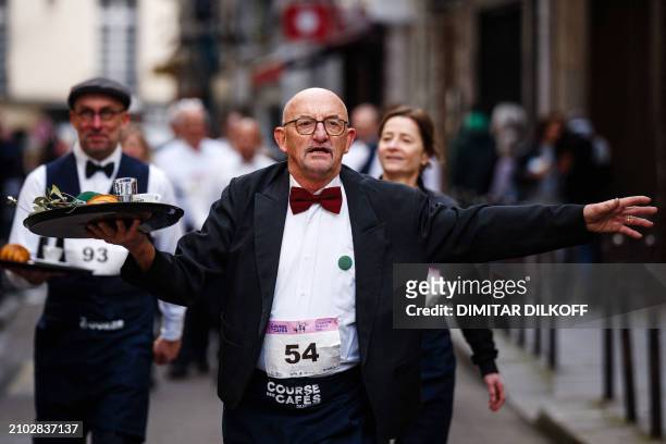 Waiters in work outfits compete in a traditionnal "Course des cafes" , in central Paris, on March 24, 2024. Around 200 participants gathered to...