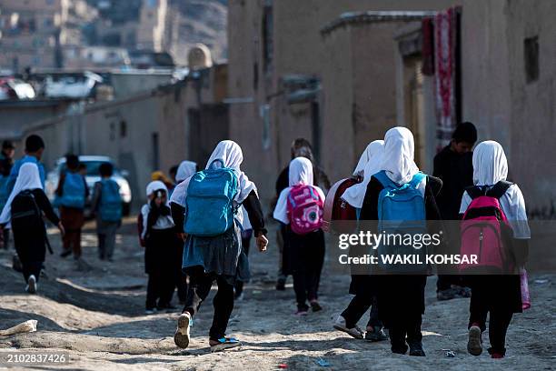 Afghan primary school girls make their way to home near the Shuhada lake in Kabul on March 24, 2024.